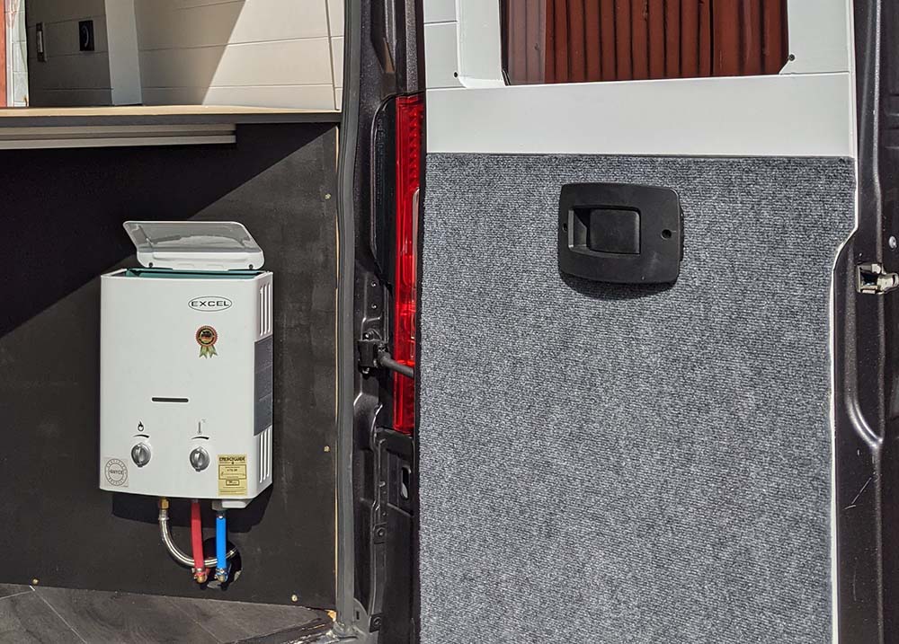 Professional installation of an Excel tankless water heater in a custom camper van by Vanpire Customs in Los Angeles, California, ensuring reliable hot water for off-grid living.