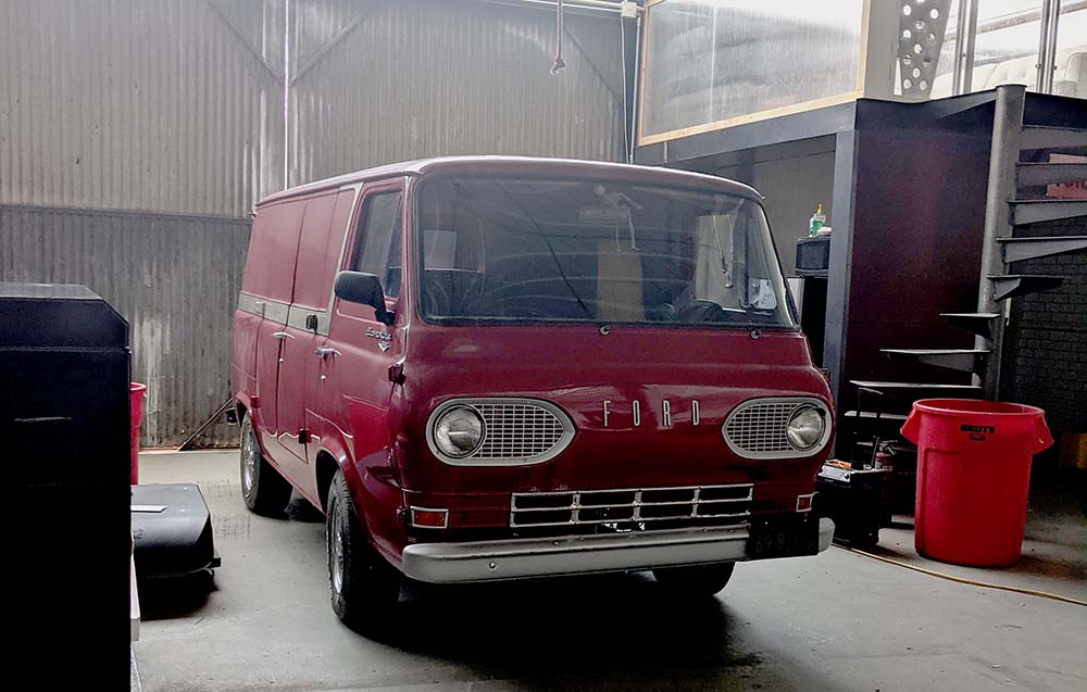 A classic red Ford van being serviced in a professional workshop, demonstrating Vanpire Customs' ability to handle vintage vehicles with dealership-level diagnostic expertise in Los Angeles, California