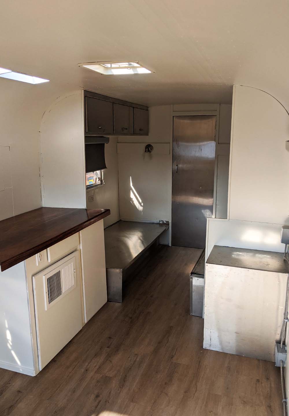 Spacious interior layout of a custom camper conversion by Vanpire Vans in Los Angeles, featuring wood flooring and functional cabinetry.
