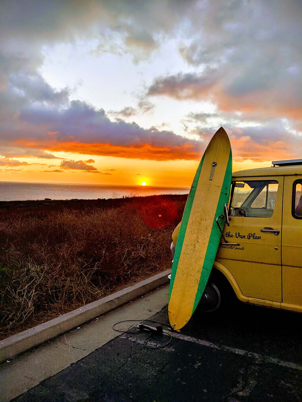 Custom camper van parked at sunset with surfboard, representing the lifestyle of Vanpire Vans conversions in Los Angeles.