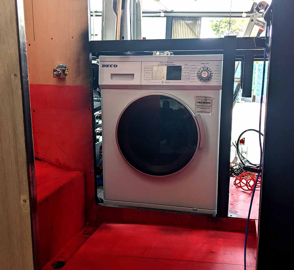Compact washer and dryer installation in a custom camper van conversion by Vanpire Vans, designed for long-term off-grid living in Los Angeles