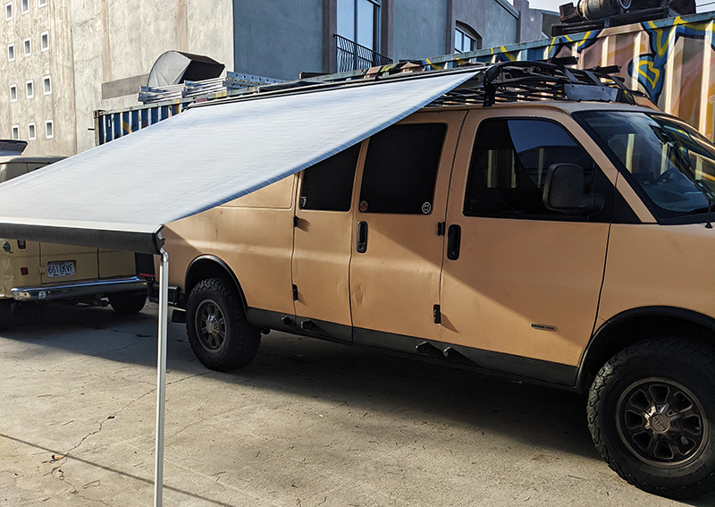 Custom camper van equipped with an external awning and heavy-duty roof rack, built for off-road travel by Vanpire Vans in Los Angeles.