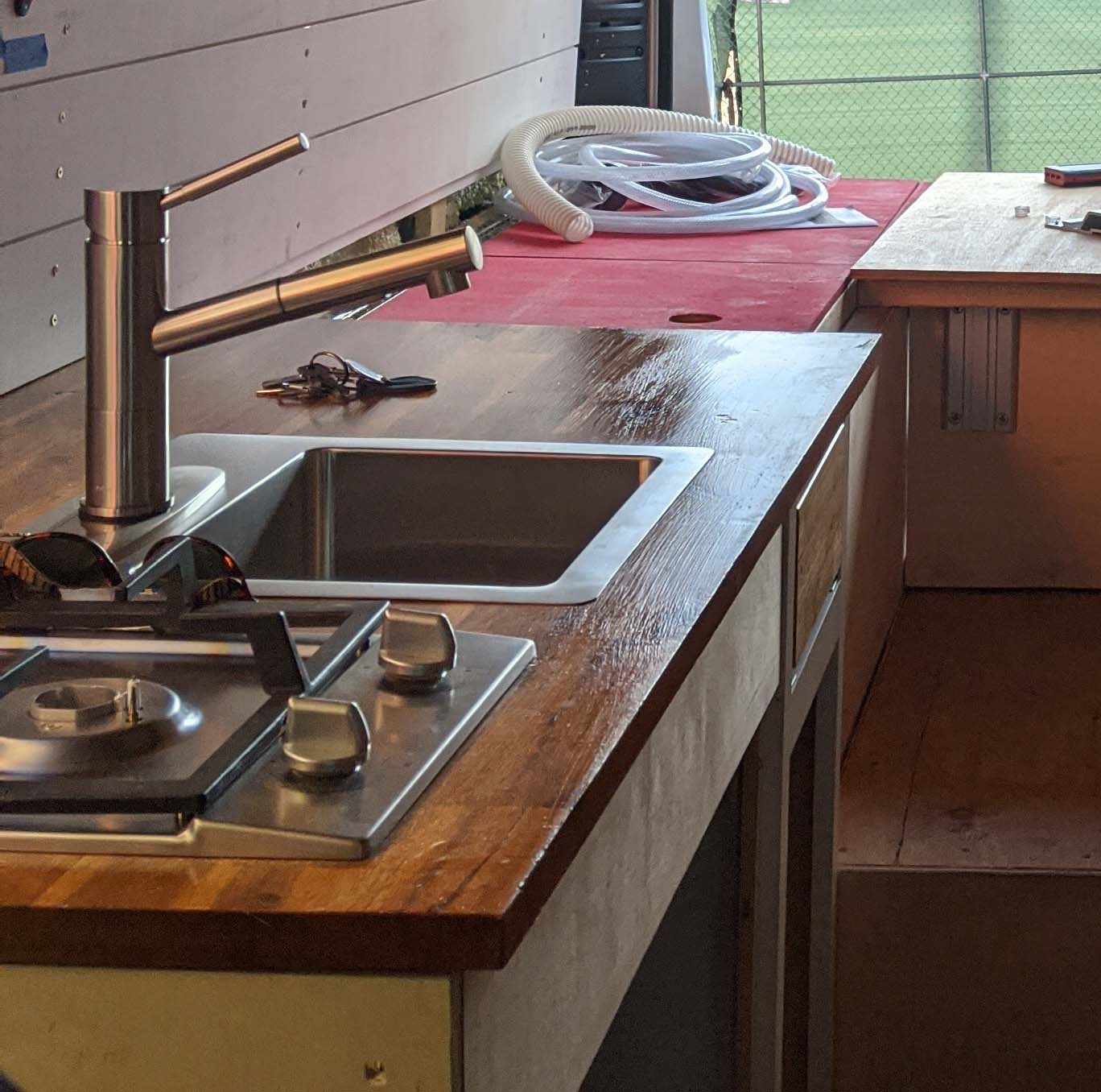 A professional-grade van conversion interior featuring custom plumbing and gas stove integration, designed by Vanpire Customs for trades, HVAC, and commercial service fleets in Los Angeles